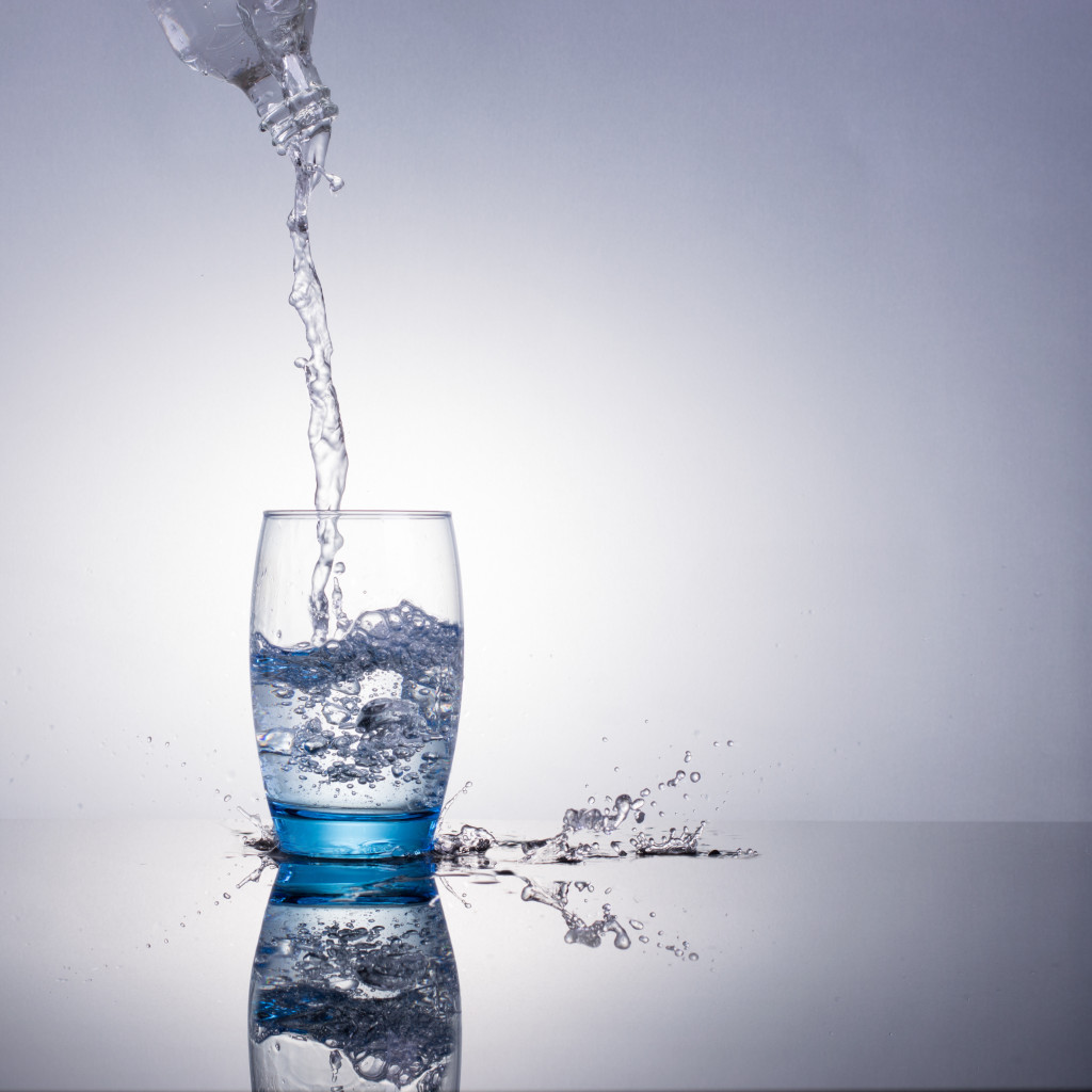 Water flowing and splashing from a glass bottle