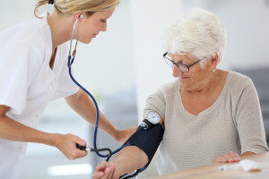Doctor checking elderly woman's blood pressure