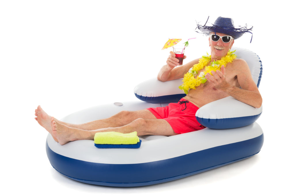 Senior man in beach hat and sunglasses enjoying a cold umbrella drink while sitting in a floating lounge. 