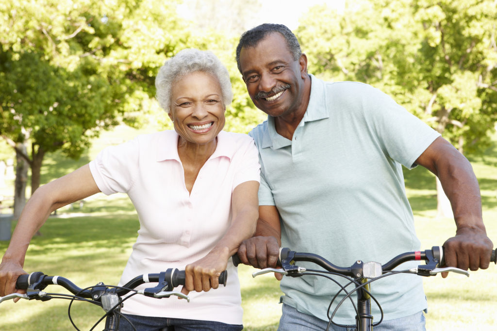 Healthy seniors ride bikes in sunny park.