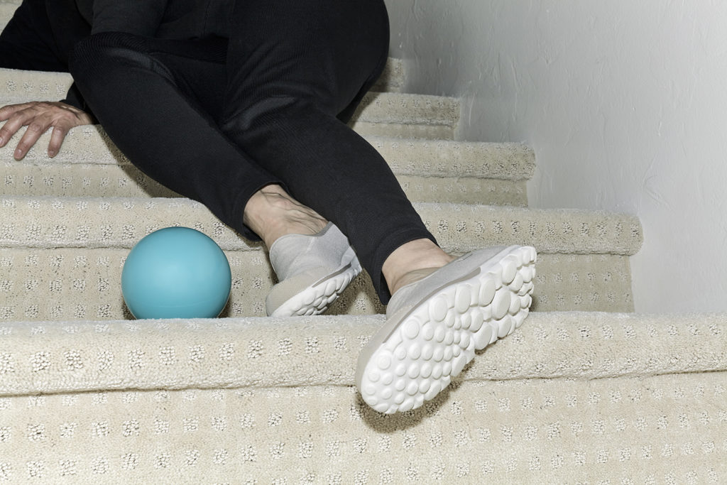 Woman's legs on carpeted stairwell with a recent fall having tripped over a ball on the steps.