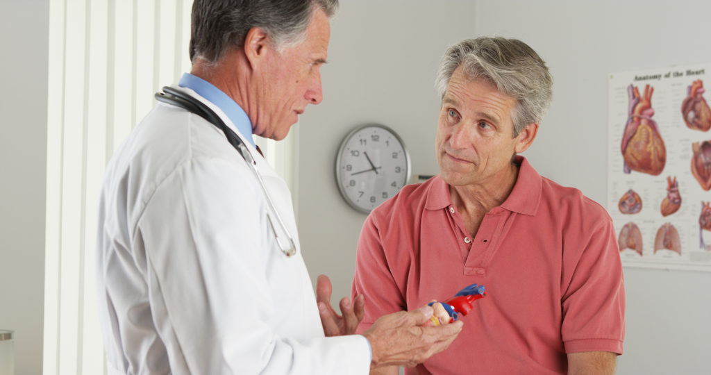 Cardiologist talking with heart patient in the doctor's office.