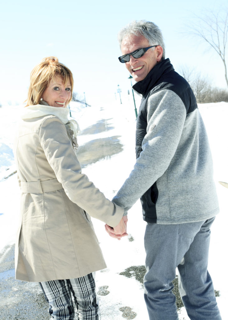 Happy senior couple walking together hand in hand on a sunny winter day.