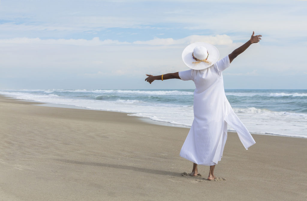 African American woman dancing on the beach.