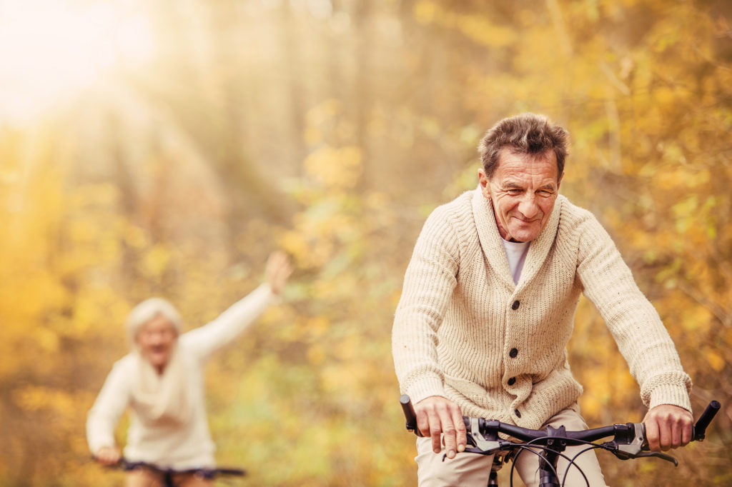 Seniors bicycling in autumn woods.