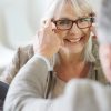 Senior woman in optical store trying eyeglasses on