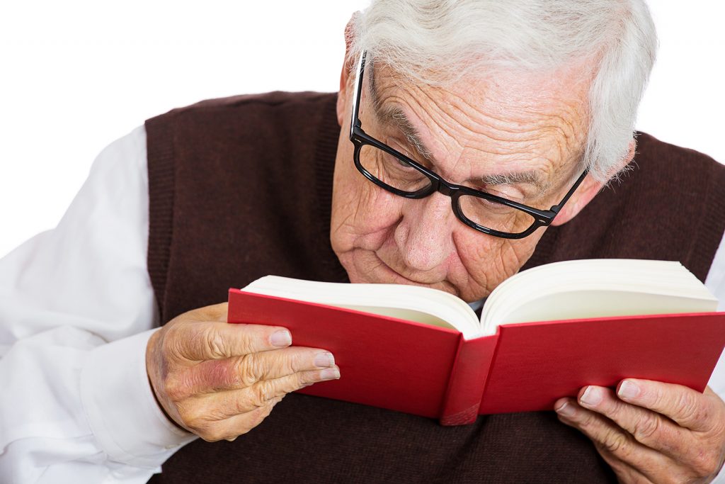 Senior man straining to read a book.