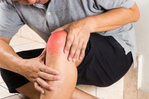 Senior man holding a painful knee joint.