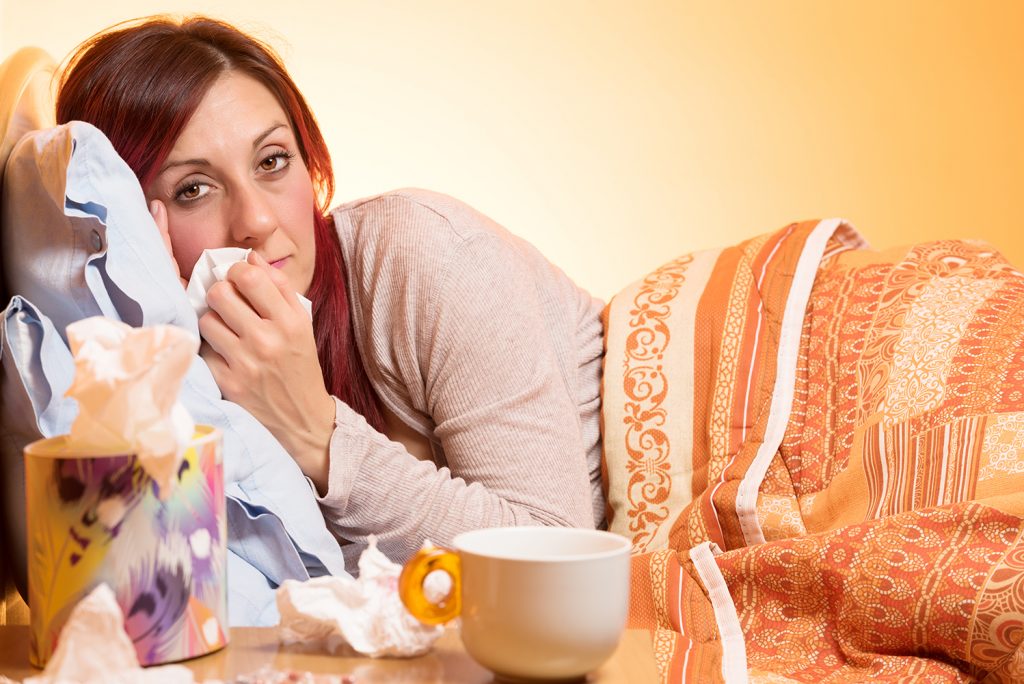 Woman snuggled in bet sick with the flu.