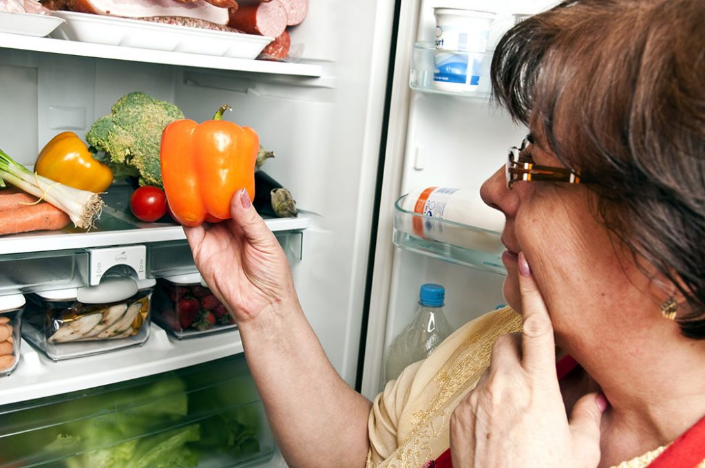 Woman opens the refrigerator and wondering what she is looking for.