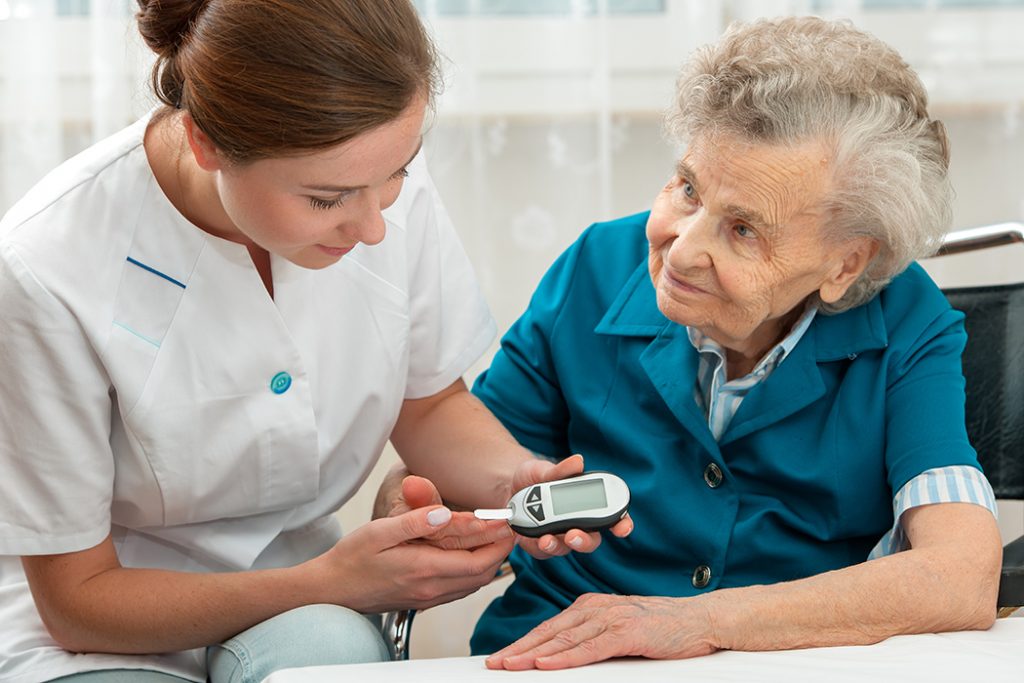 Nurse helping patient measure blood sugar level.