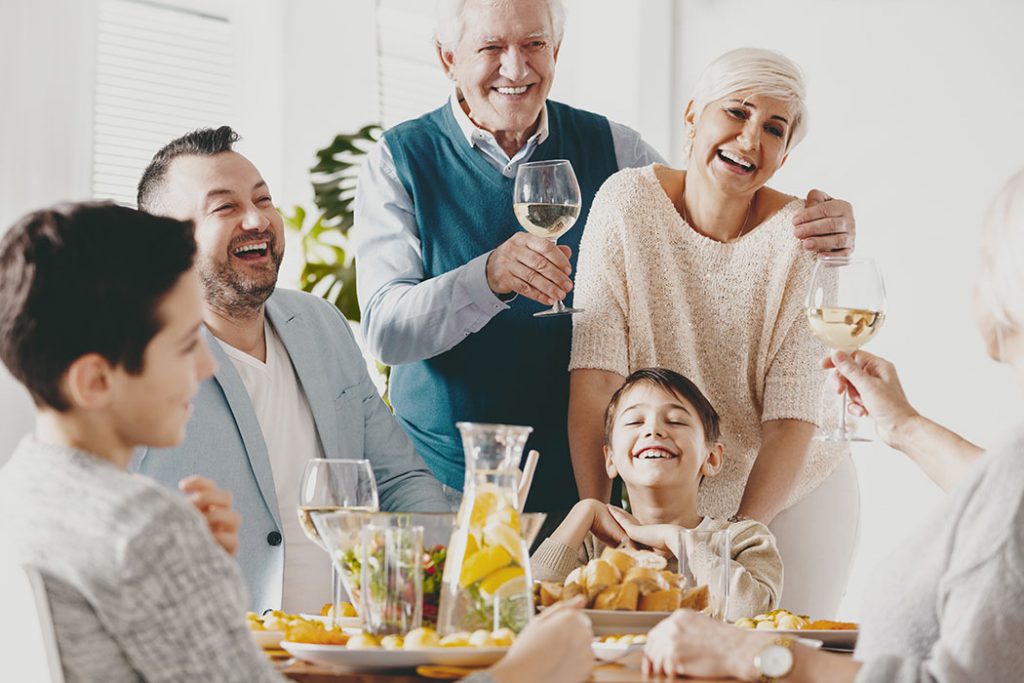 Smiling grandfather and grandmother making toast during family meeting with happy kid