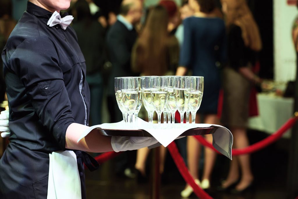 Waiter holding a tray with glasses of vine at party