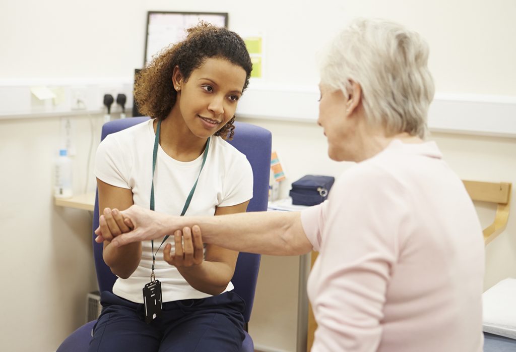 Therapist working with senior woman on wrist and hand pain.