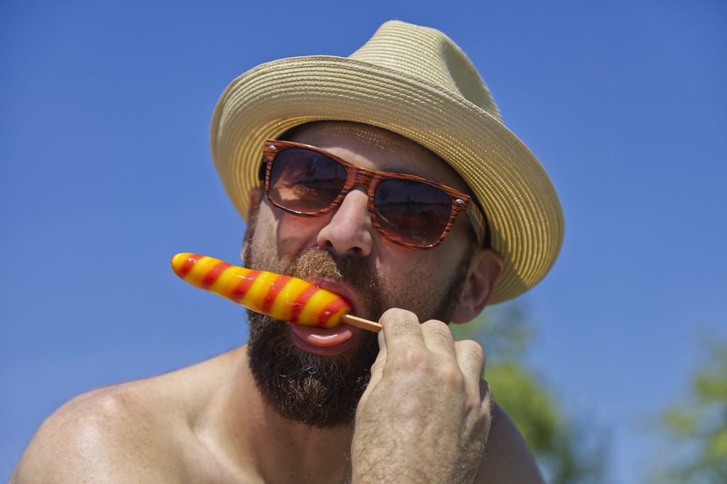 Senior man eating a popsicle on a very hot day.