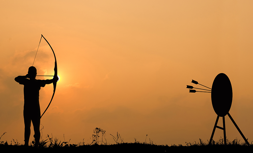 Silhouette archery shoots a bow at the target in sunset sky and cloud.