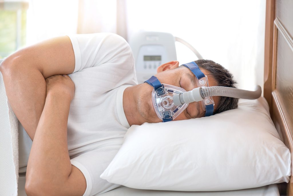 Man sleeping in bed wearing CPAP mask ,sleep apnea therapy