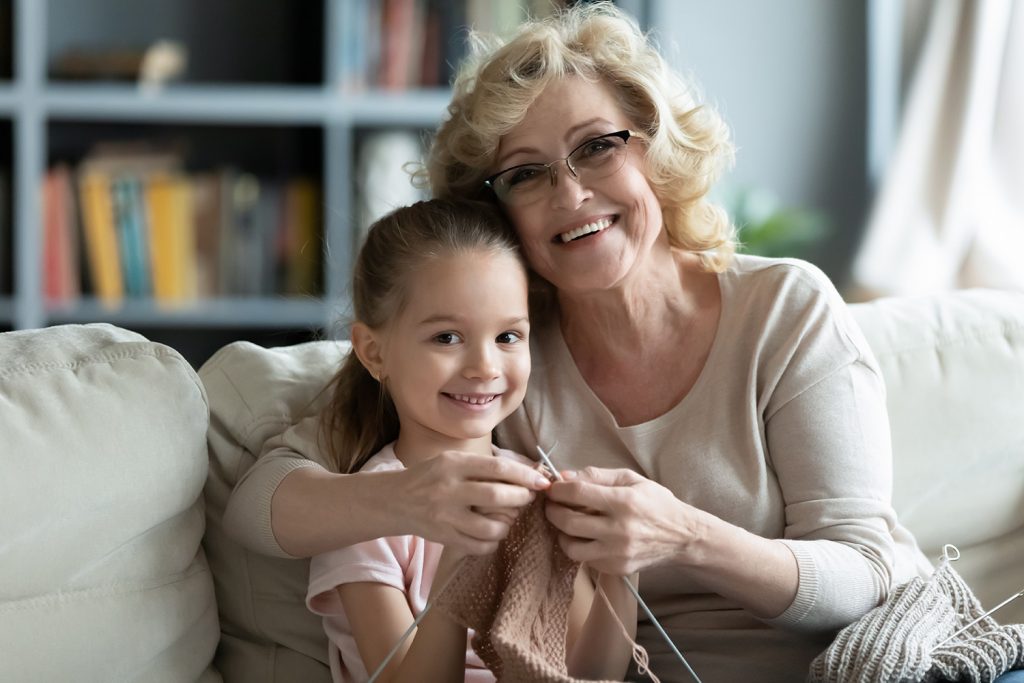 Grandmother teaches young granddaughter how to knit.