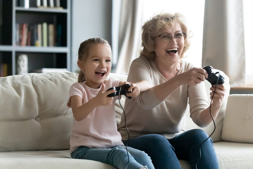 Grandmother and young granddaughter play video games.
