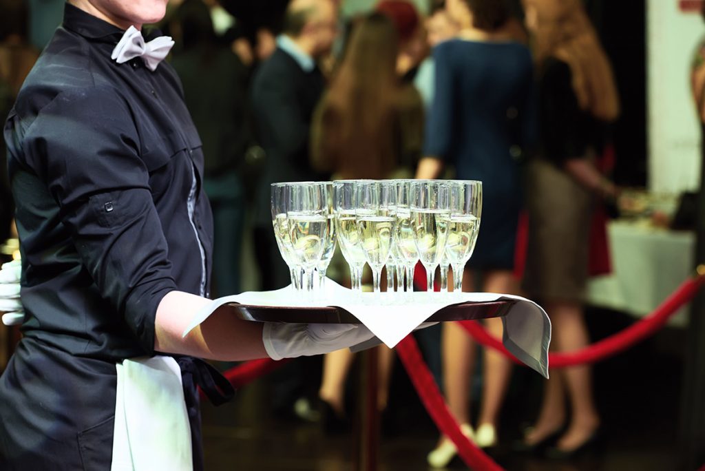 Server brings champagne on tray at holiday party.