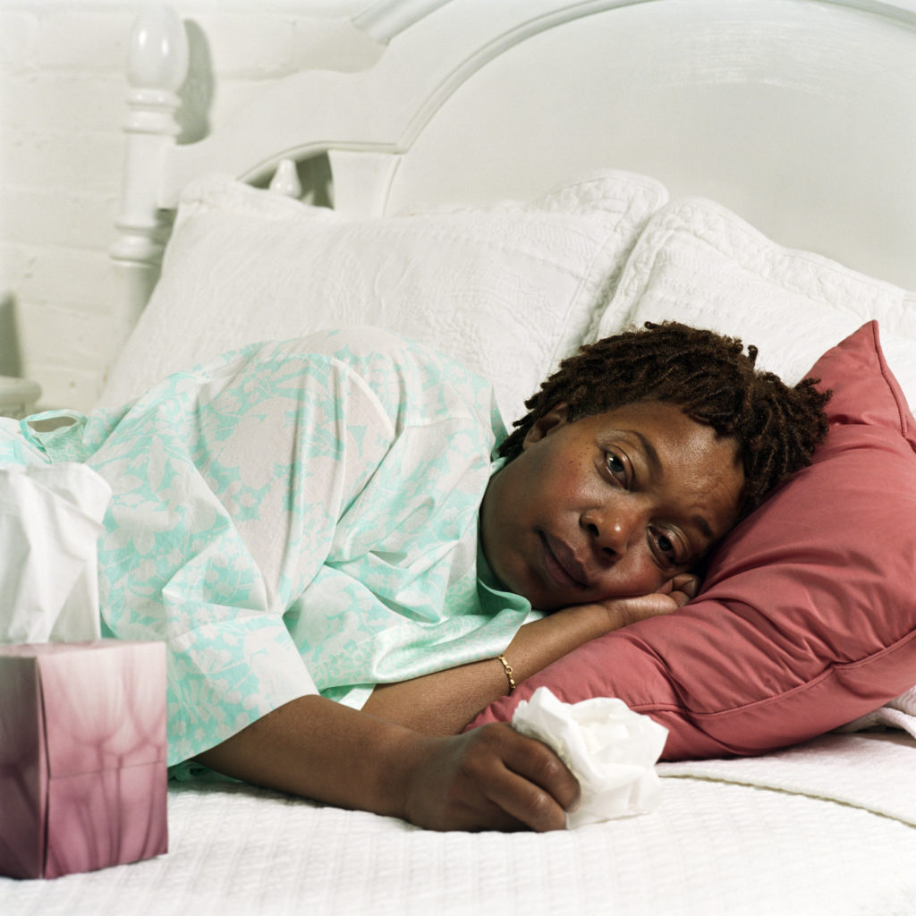 African American woman sick in bed with the flu - AW Health 