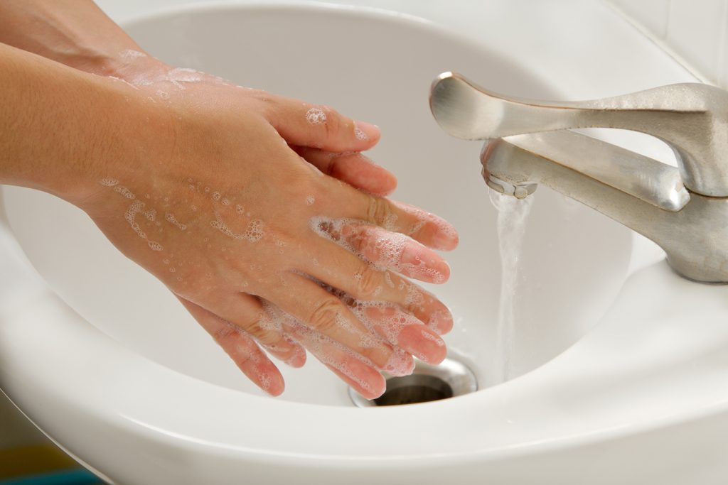 Washing hands in sink with soap and water.
