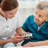 Nurse helping patient measure blood sugar level.