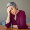 Woman suffering from depression holds head with hand.